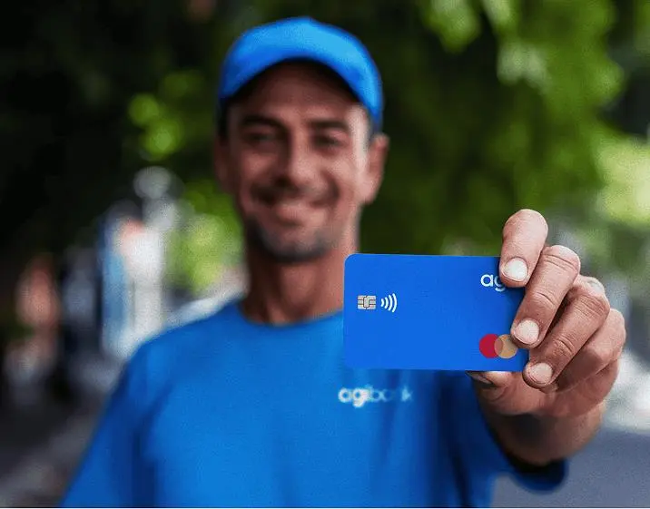 Funcionário do Agibank segurando o cartão Agi Consignado.