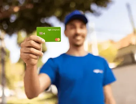 Funcionário do Agibank segurando o cartão Agi Consignado.